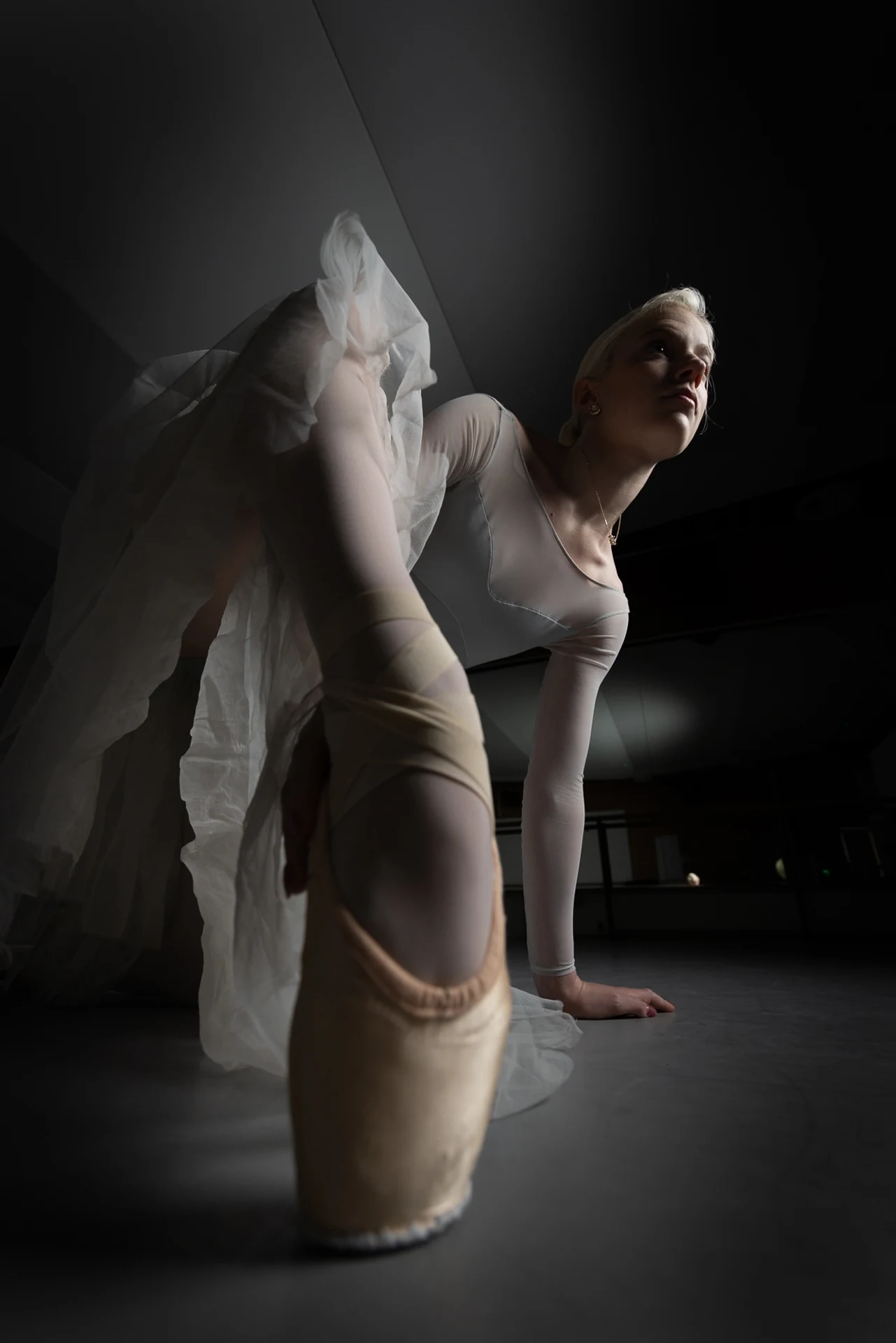 Dancer seated in white tulle, viewed from a low angle