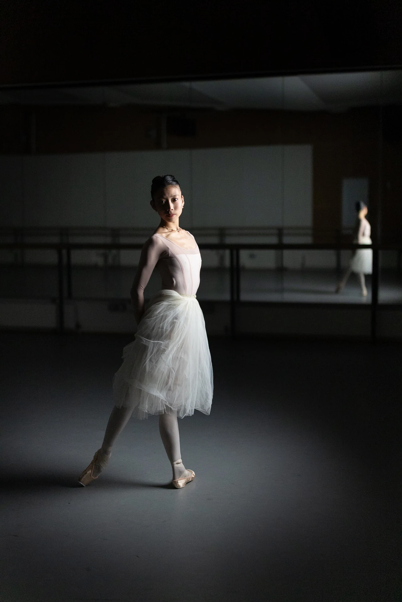 Dancer standing in white tulle beside the studio windows